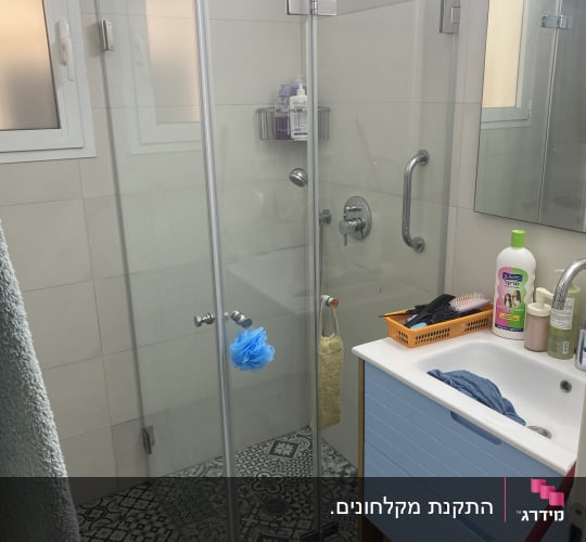 מקלחת זכוכית עם כיור ומראה בחדר אמבטיה